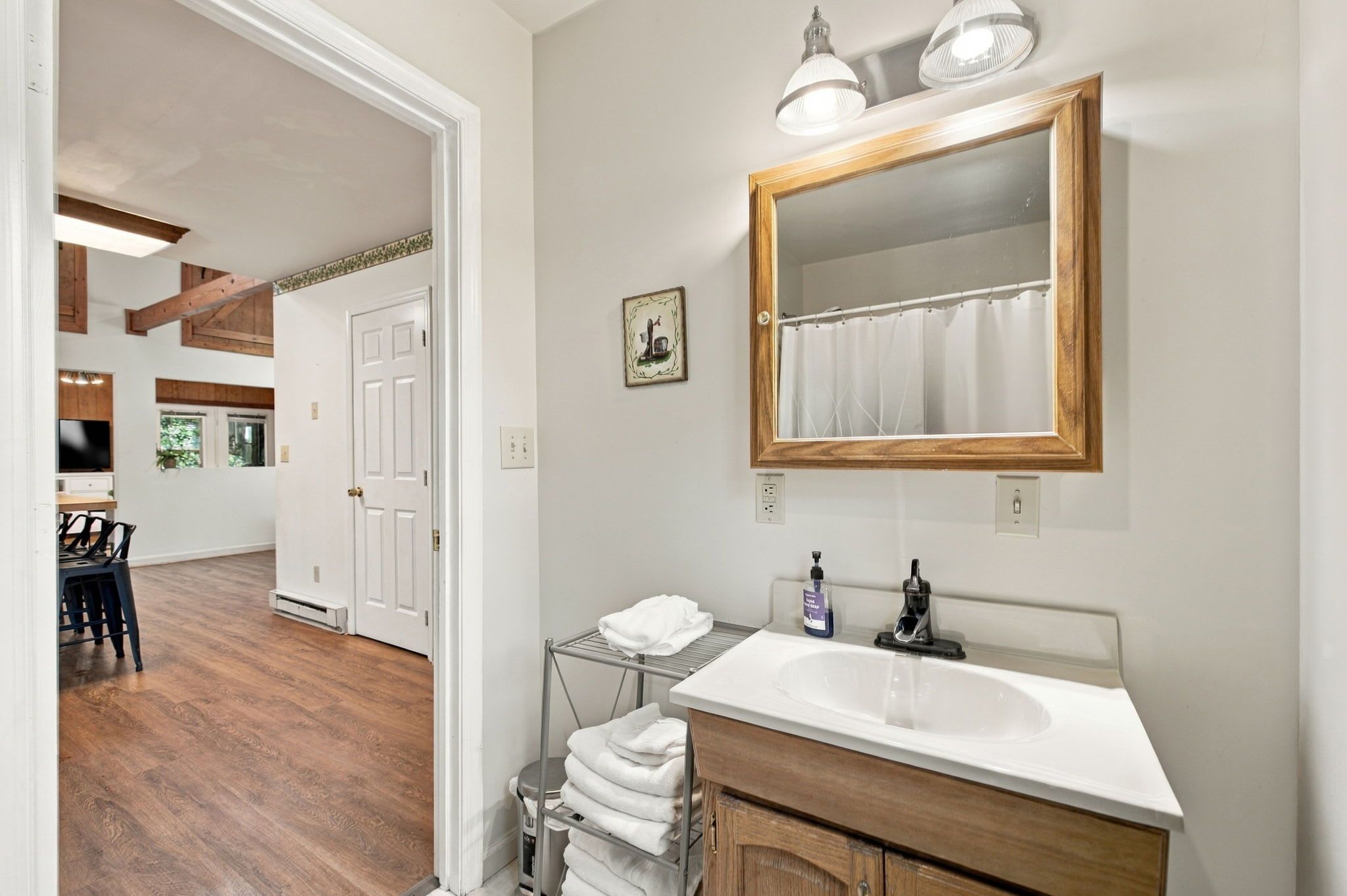 Une salle de bain avec un meuble-lavabo en bois, un grand miroir et un porte-serviettes.
