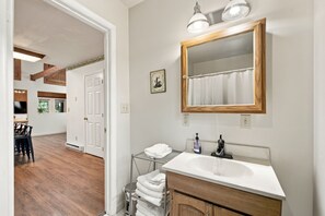 A bathroom with a wooden vanity, a large mirror, and a towel rack.