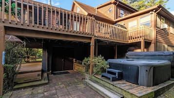 Eine Holzterrasse mit Whirlpools und überdachtem Bereich.