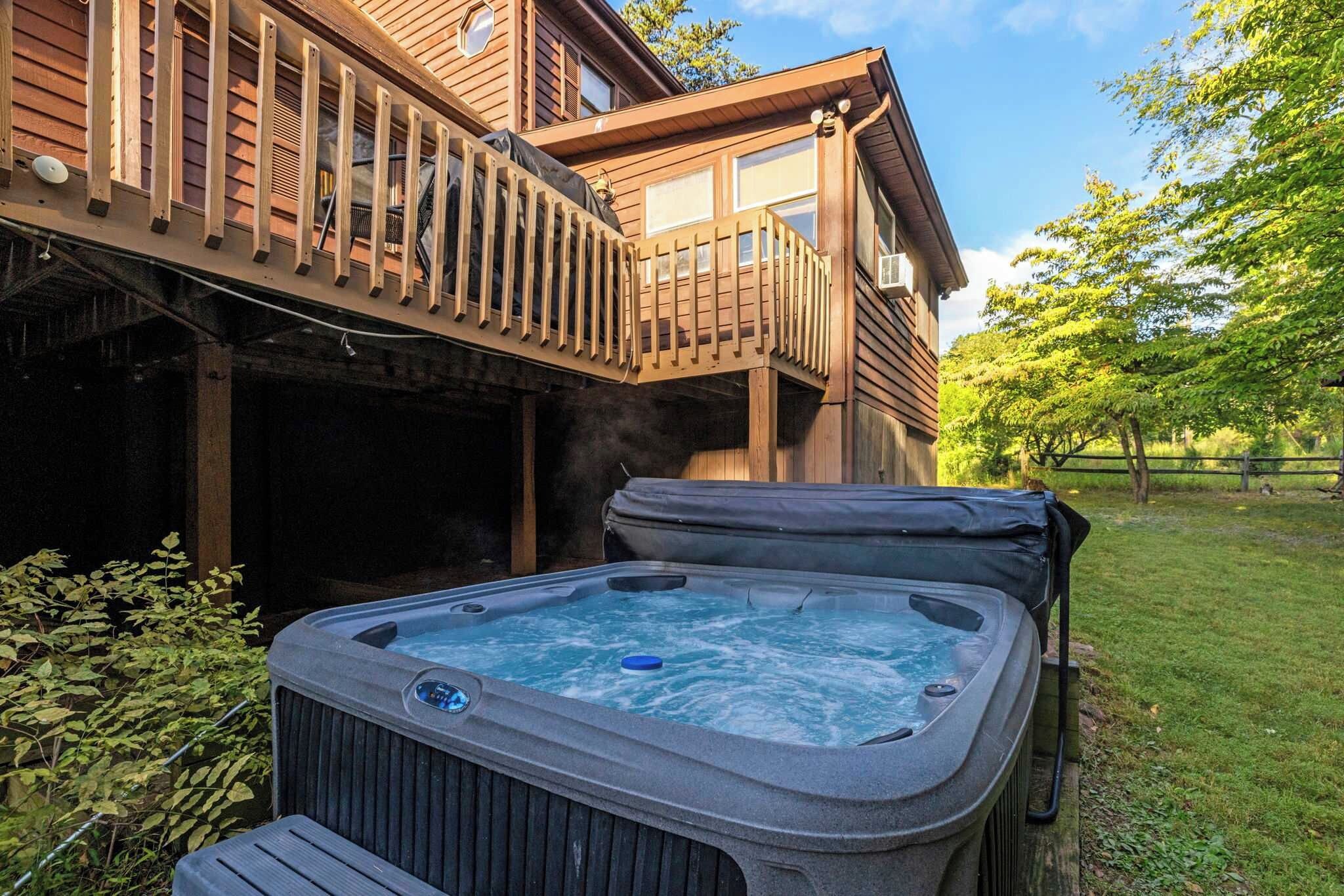 Un bain à remous à l’extérieur d’une maison en bois, avec une terrasse.