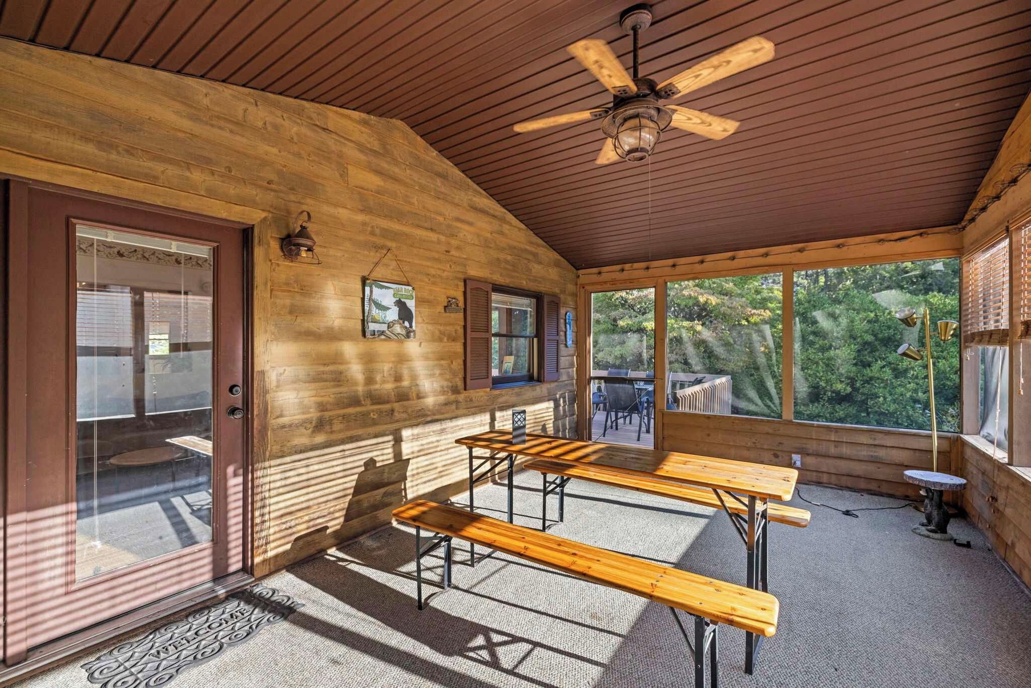 A wooden cabin interior with a ceiling fan, wooden benches, and a view of the outdoors.