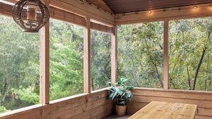 Un interior de madera con ventanas amplias, una mesa de madera y una lámpara colgante.