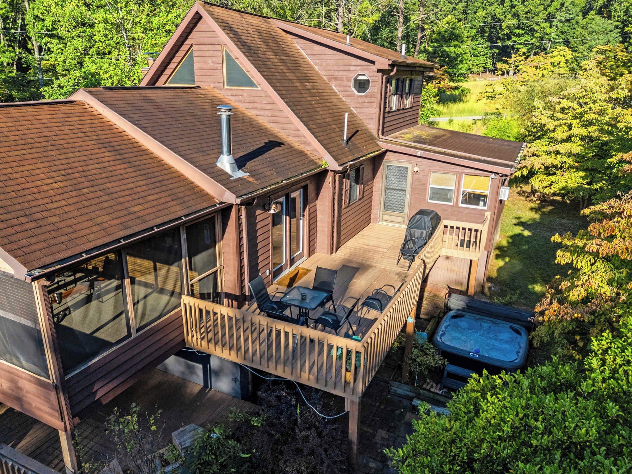 A two-story house with a deck, outdoor seating, and a hot tub.