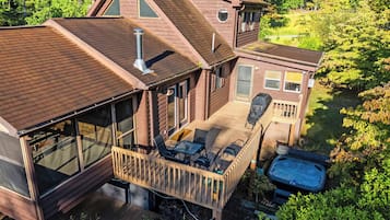 A two-story house with a deck, outdoor seating, and a hot tub.