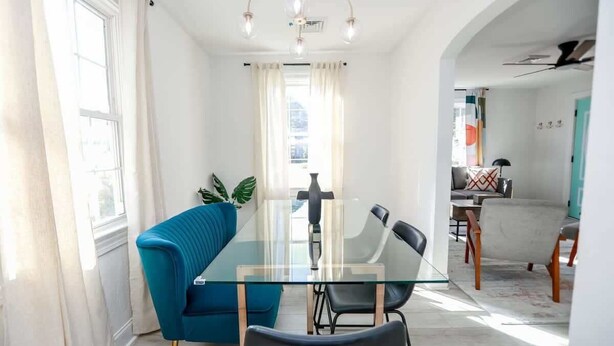 Un espace repas moderne avec une table en verre, une chaise recouverte de tissu bleu et des chaises noires.