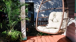 Une chaise en osier dotée d’un siège et d’un dossier rembourrés, placée sur une terrasse en bois.