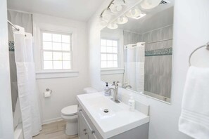 A modern bathroom with a white vanity, a large mirror, and a shower area.