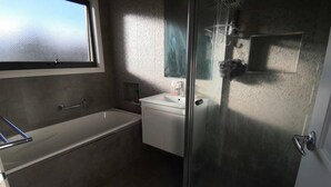 A bathroom with a bathtub, a sink, and a glass shower enclosure. - A Cozy room in Center of Glen (Glen Waverley)