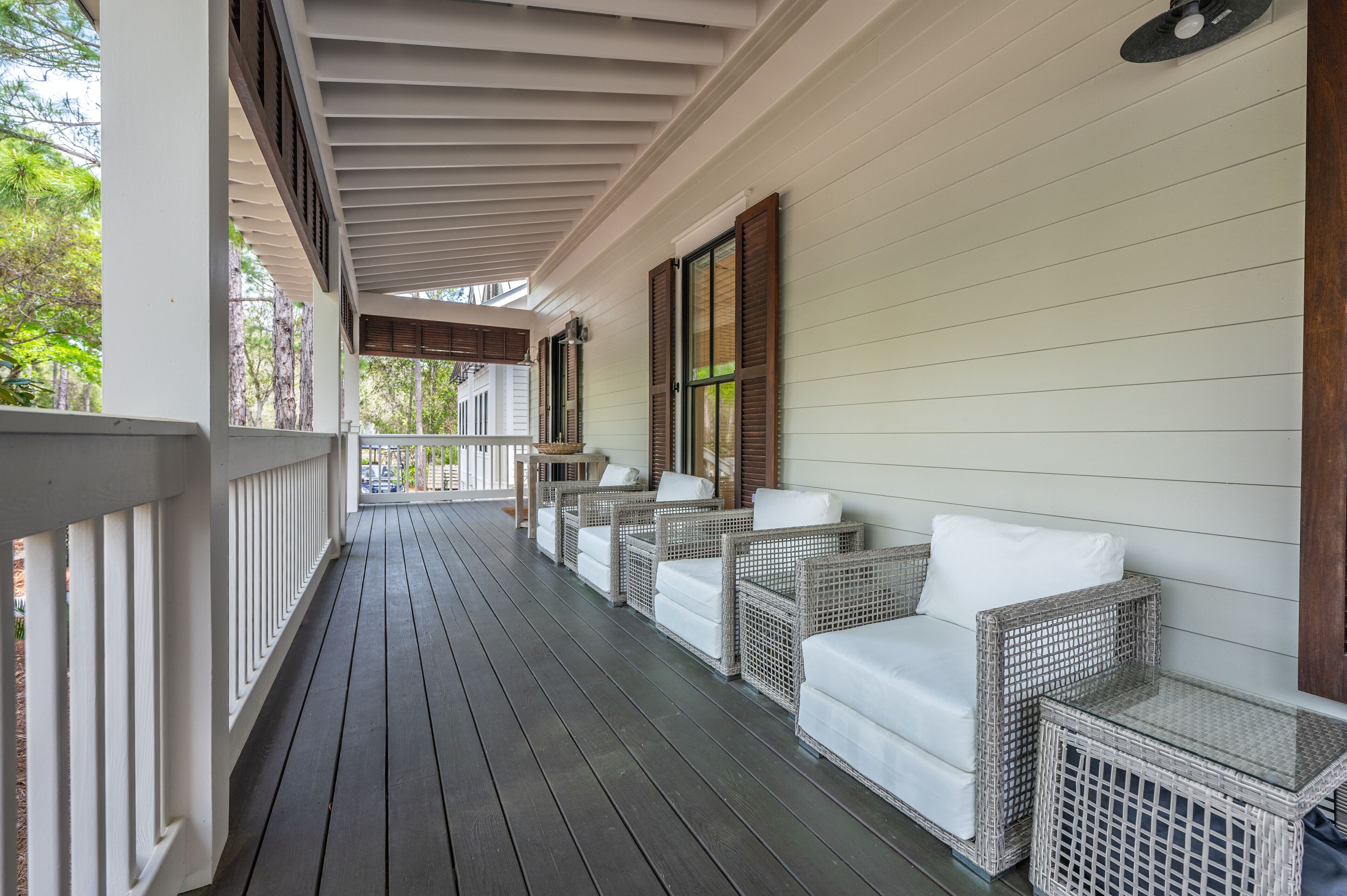 A covered porch with wicker furniture and a railing.