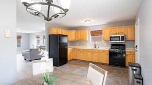 A modern kitchen with wooden cabinets, a black refrigerator, a microwave, and a stove. There is a dining table with chairs and a potted plant. - Gorgeous Waterfront 2:1 - 2 houses in 1 building. (New Haven)
