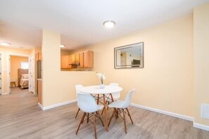 A dining area with a white table and chairs, beige walls, and wooden flooring. - Gorgeous Waterfront 2:1 - 2 houses in 1 building. (New Haven)