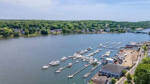 A marina with multiple docks and boats, surrounded by a forested area and residential buildings. - Gorgeous Waterfront 2:1 - 2 houses in 1 building. (New Haven)