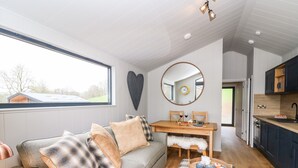Un espacio habitable moderno y funcional, con sofá, mesa de comedor y zona de cocina.