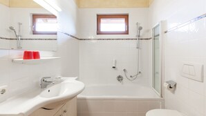 A bathroom with a sink, mirror, shower, and toilet. - Noichl's Hotel Garni  (Sankt Johann in Tirol)