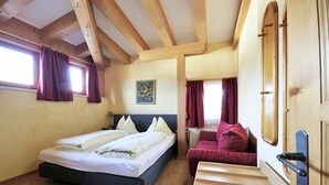 A bedroom with a bed, a wooden door, and a window with curtains. - Noichl's Hotel Garni  (Sankt Johann in Tirol)