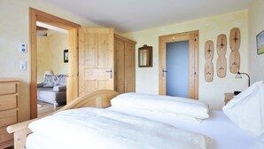 A bedroom with a wooden bed, a wooden wardrobe, and a door with a mirror. - Noichl's Hotel Garni  (Sankt Johann in Tirol)
