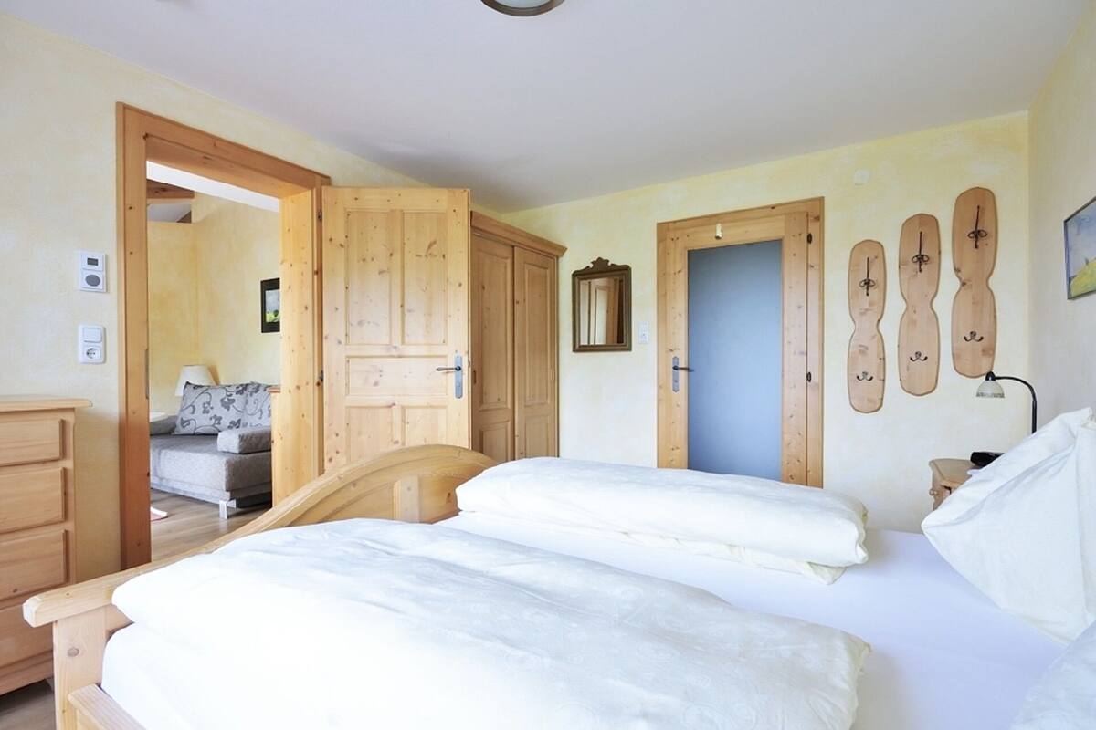 A bedroom with a wooden bed, a wooden wardrobe, and a door with a mirror.