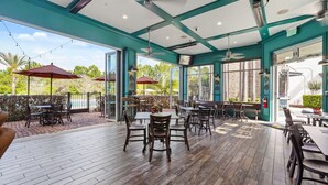An outdoor patio area with tables and chairs, large windows, and a view of the outdoors. - Blue Harbour Retreat: Private Pool, Free BBQ Grill (Davenport)