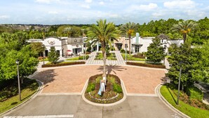 A hotel entrance with a central palm tree, a driveway, and a parking lot. - Blue Harbour Retreat: Private Pool, Free BBQ Grill (Davenport)