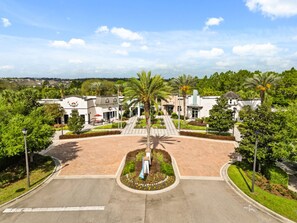 A hotel entrance with a central palm tree, a driveway, and a parking lot.