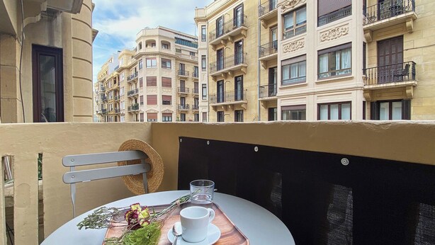 A balcony with a table set for two, featuring a cup, saucer, and a small bouquet of flowers. - Kubo by FeelFree Rentals (San Sebastian)