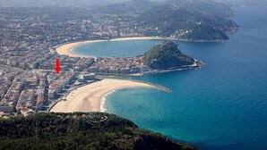 An aerial view of a coastal city with a prominent beach, a small island, and a dense urban area. - Kubo by FeelFree Rentals (San Sebastian)