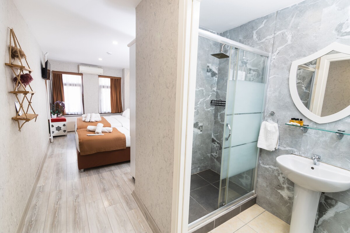 A modern bathroom with a glass shower, a marble wall, and a white sink.