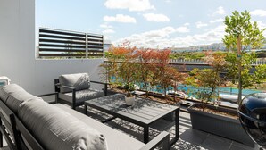 Een modern terras buiten met uitzicht op een zwembad, met een bank, stoelen en een tafel.