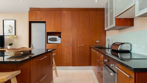 Een moderne keuken met houten kastjes, een zwart aanrecht en een magnetron.