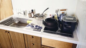 A kitchen with a sink, stove, and various utensils.