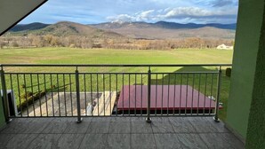 A balcony with a view of a green field and mountains. - Hotel Babic (Plitvicka Jezera)
