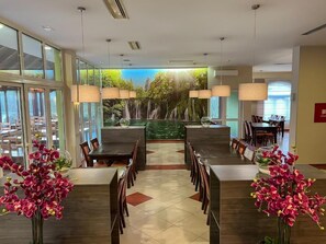 A modern dining area with a central waterfall feature, surrounded by tables and chairs. - Hotel Babic (Plitvicka Jezera)