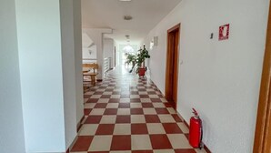 A hotel corridor with a checkered floor, a fire extinguisher, and a door on the right. - Hotel Babic (Plitvicka Jezera)