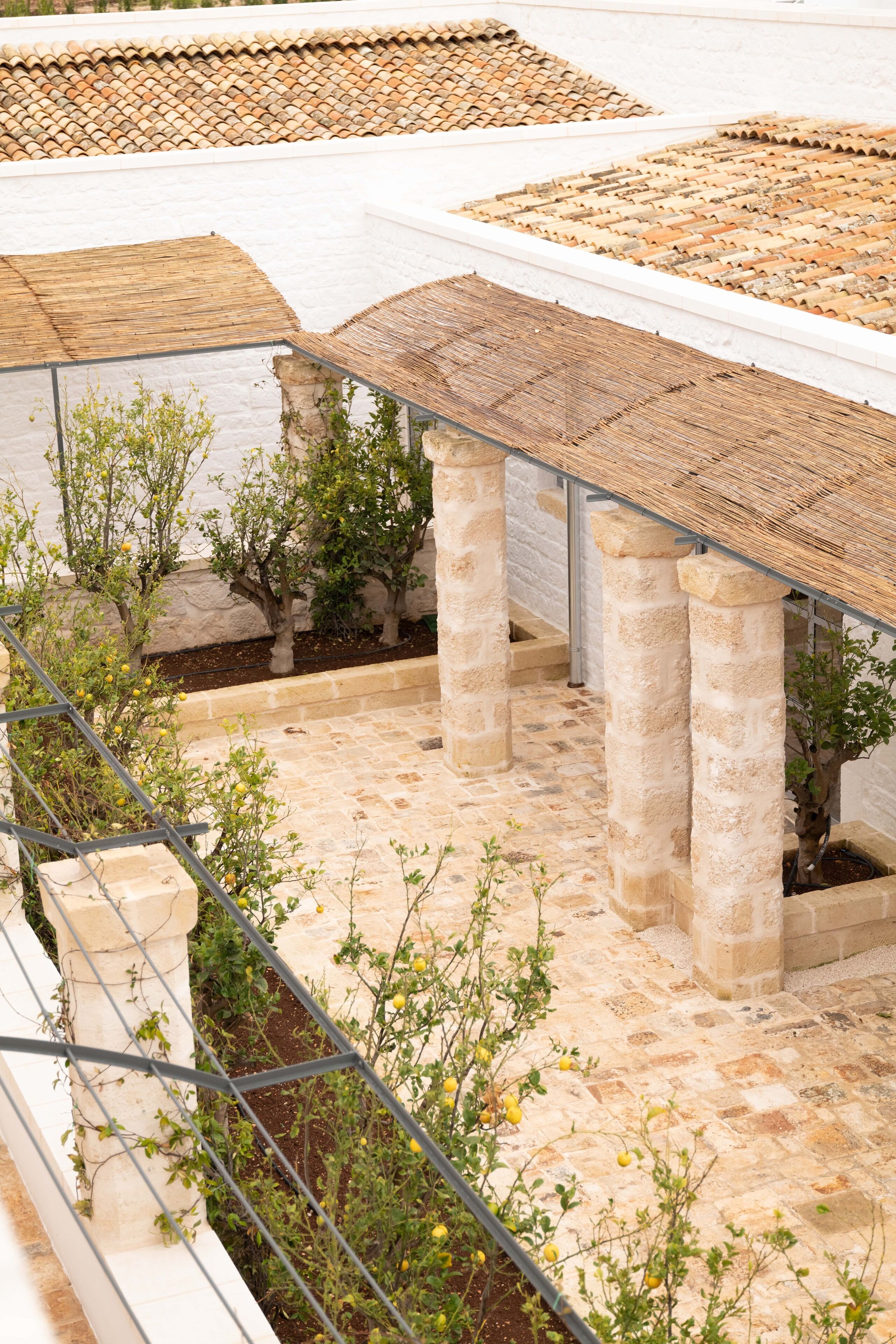 Een dakbalkon met stenen zuilen, een pergola en plantenpotten.