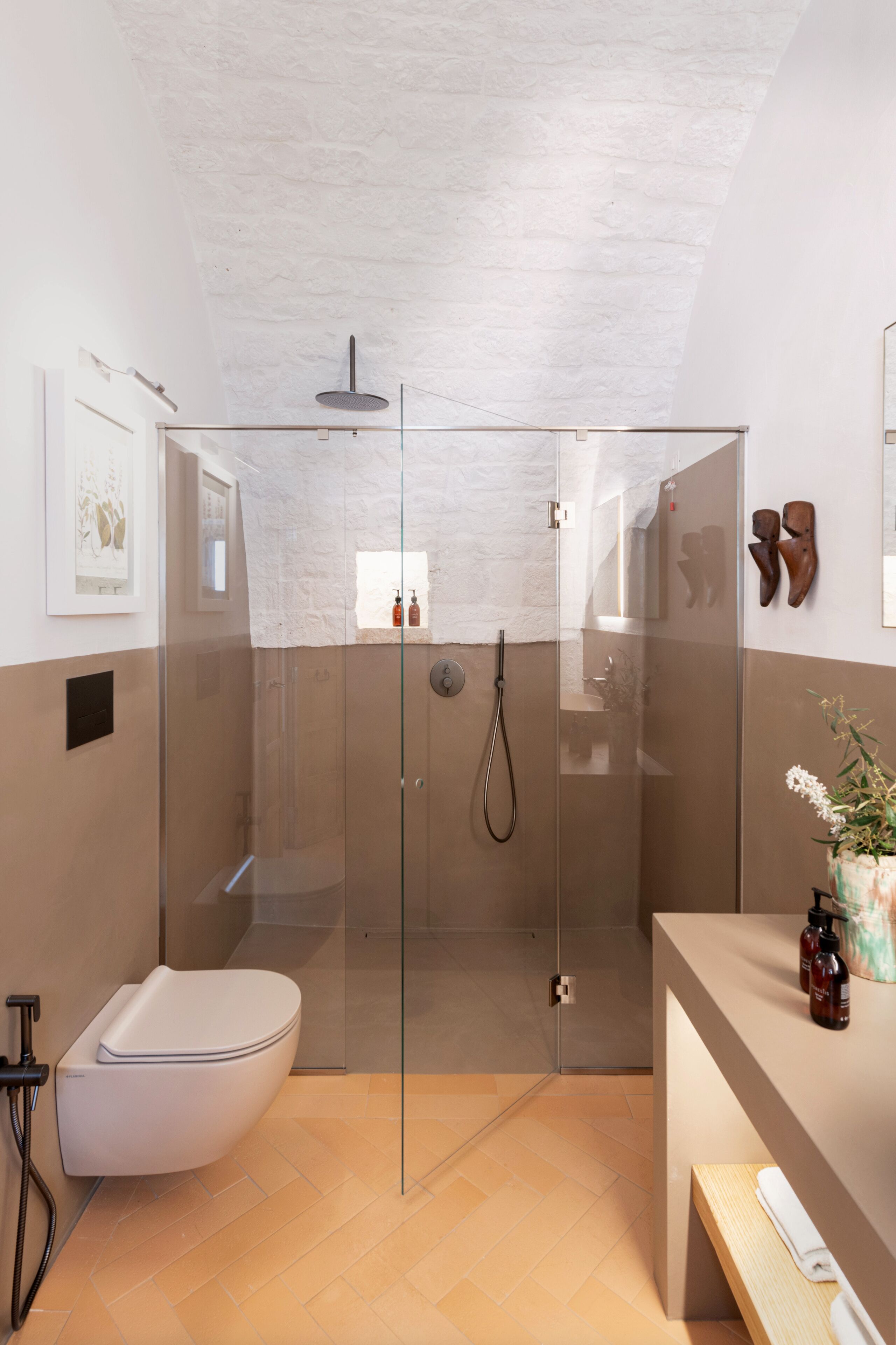 A modern bathroom with a glass-enclosed shower, a white toilet, and a wooden vanity.