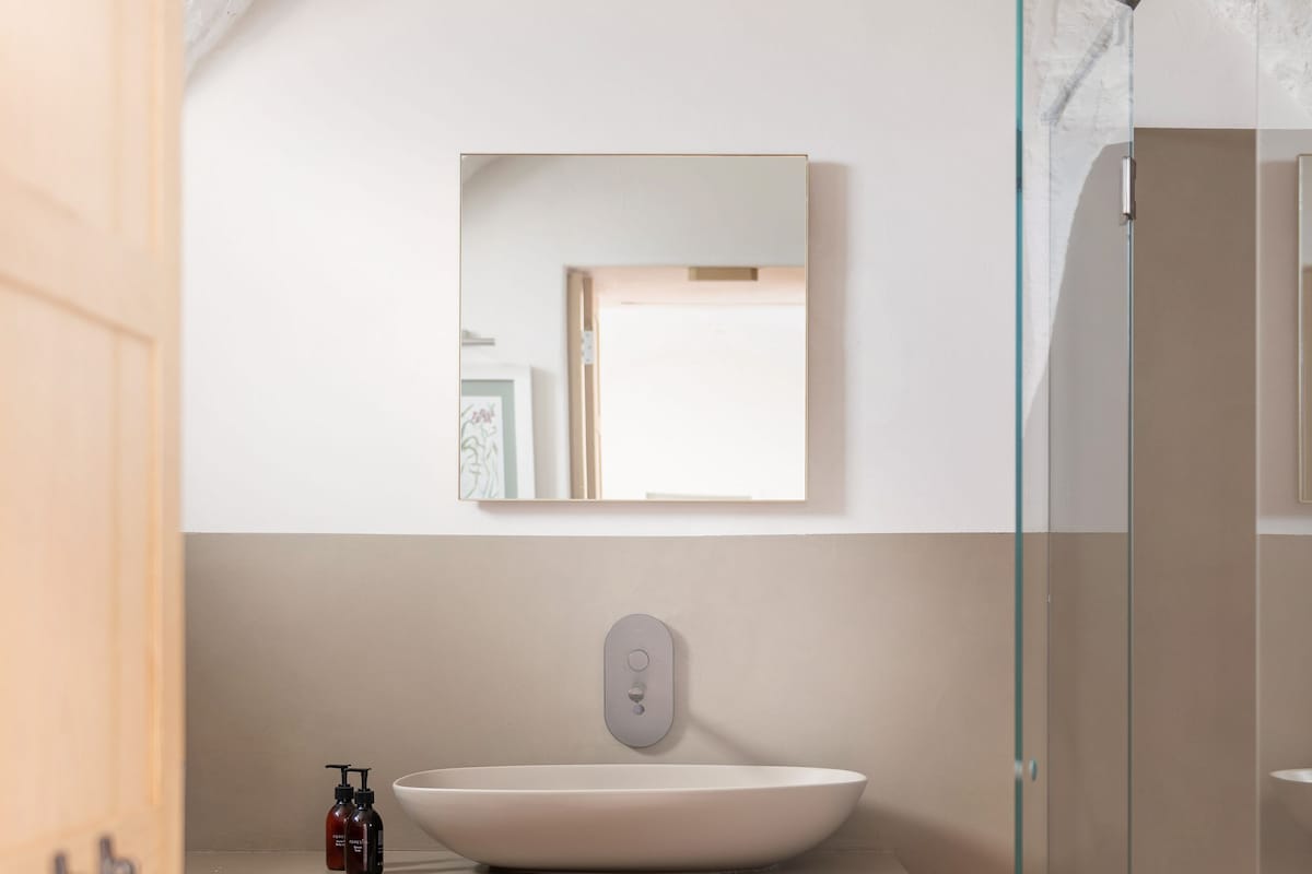 A modern bathroom with a large white sink, a glass shower enclosure, and a wooden vanity.