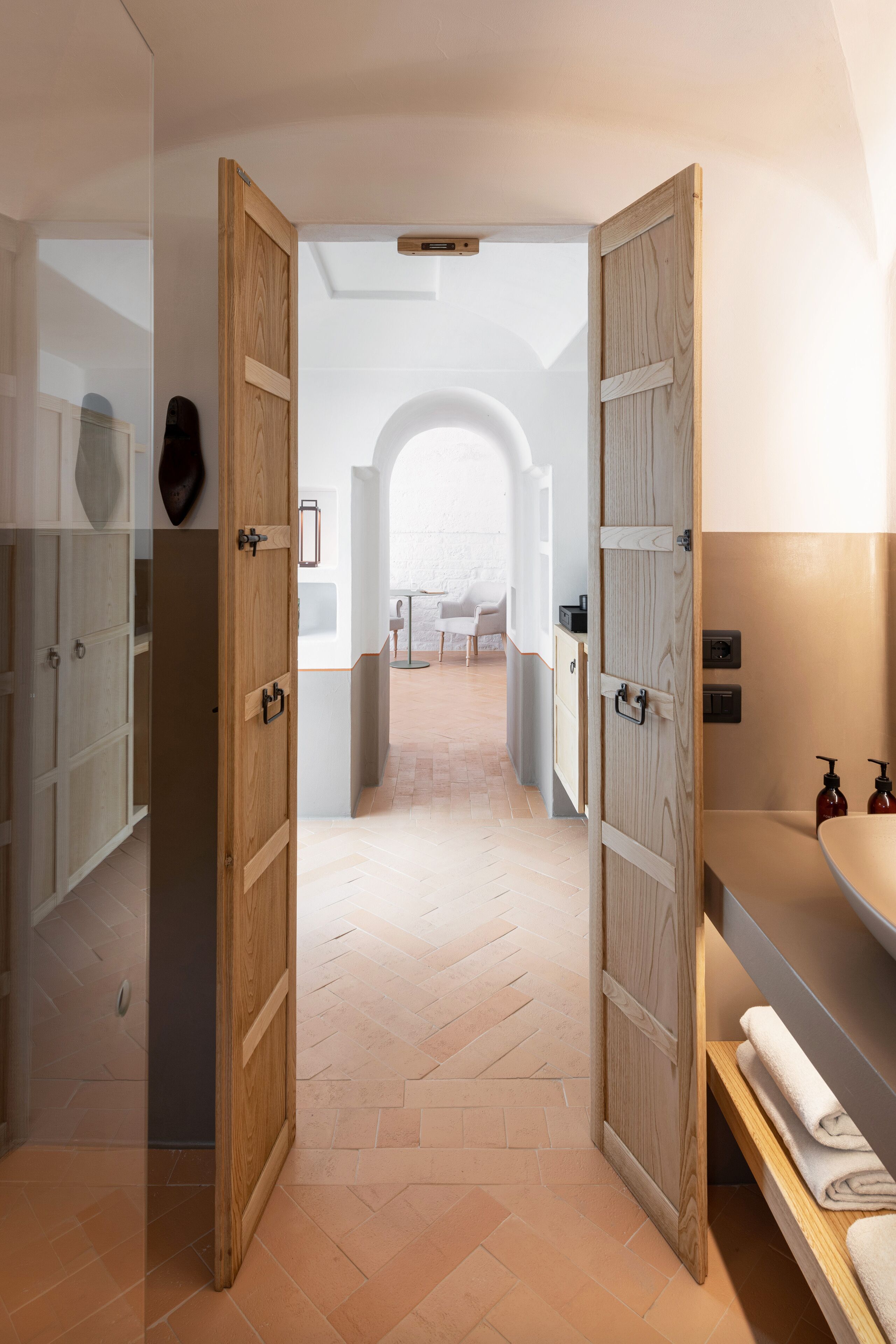 Un baño moderno con puertas de madera, un espejo grande y un lavamanos con artículos de tocador.