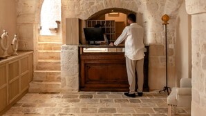 Une pièce aux murs de pierre, avec un bureau en bois et une personne debout devant.