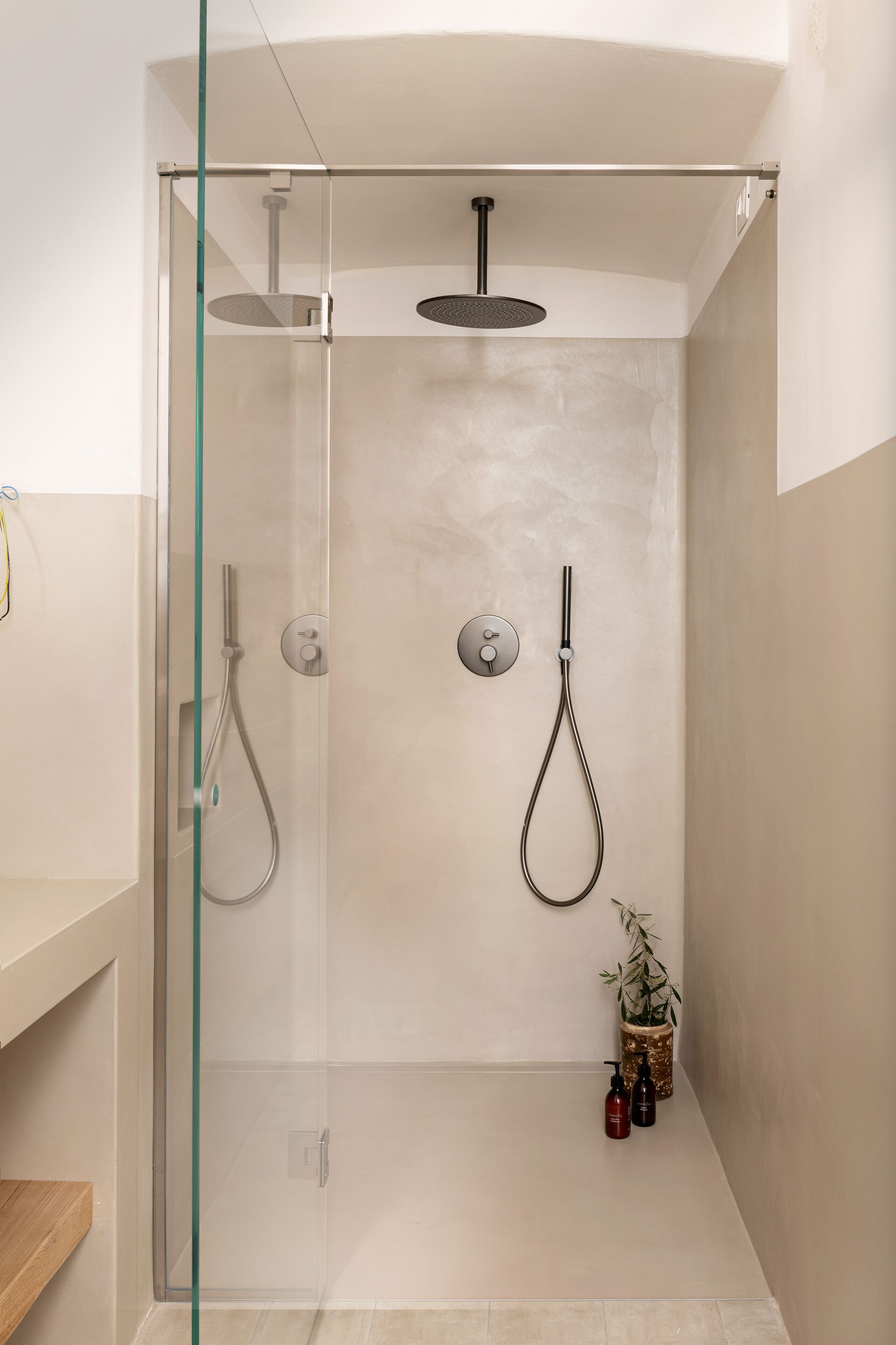 A modern shower with a glass door, a handheld showerhead, and a wall-mounted faucet.