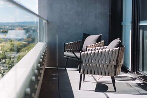 A balcony with two chairs and a view of a cityscape.