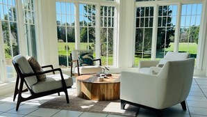 A sunlit room with large windows, a round wooden coffee table, and two armchairs. - 6BR Waterfront Estate | Private Dock, Firepit, Screened Porch & Beach Access (Sherwood)