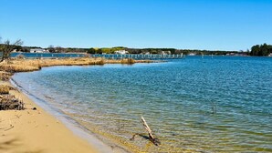 A sandy beach with clear water and a bridge in the background. - 6BR Waterfront Estate | Private Dock, Firepit, Screened Porch & Beach Access (Sherwood)