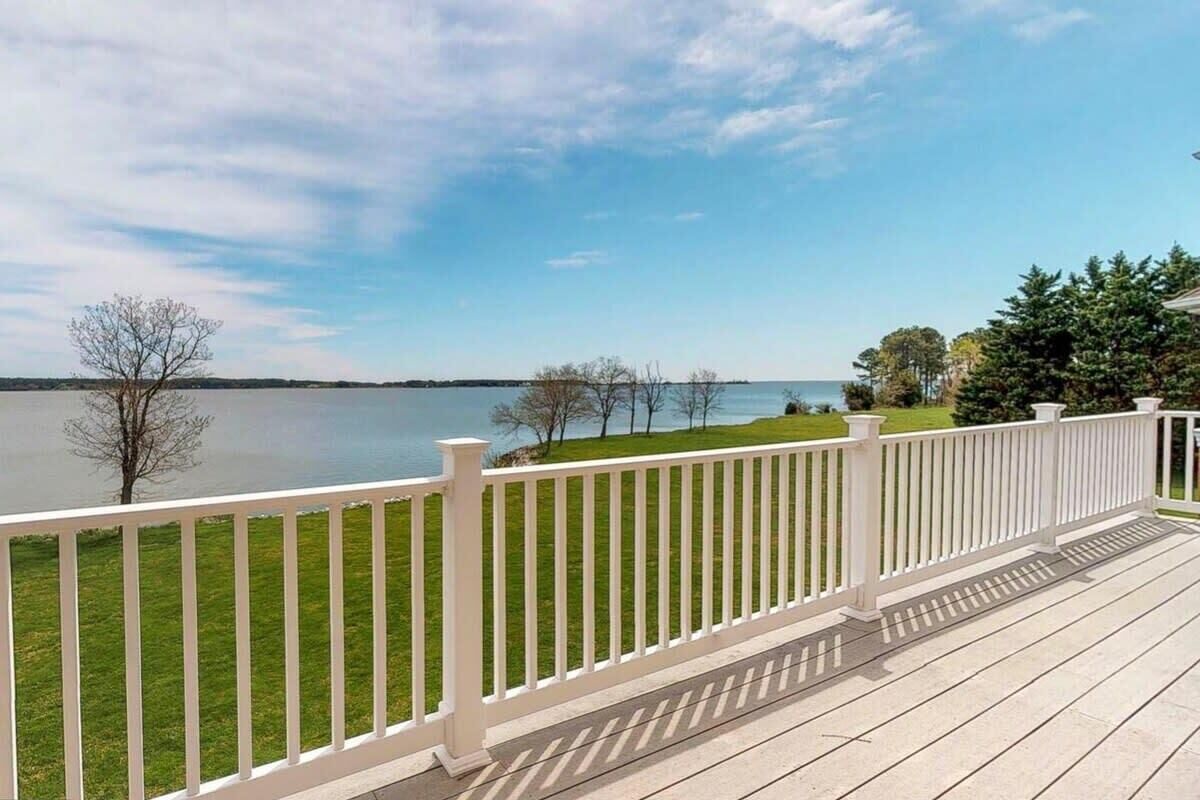 A wooden deck with a white railing overlooking a lake.