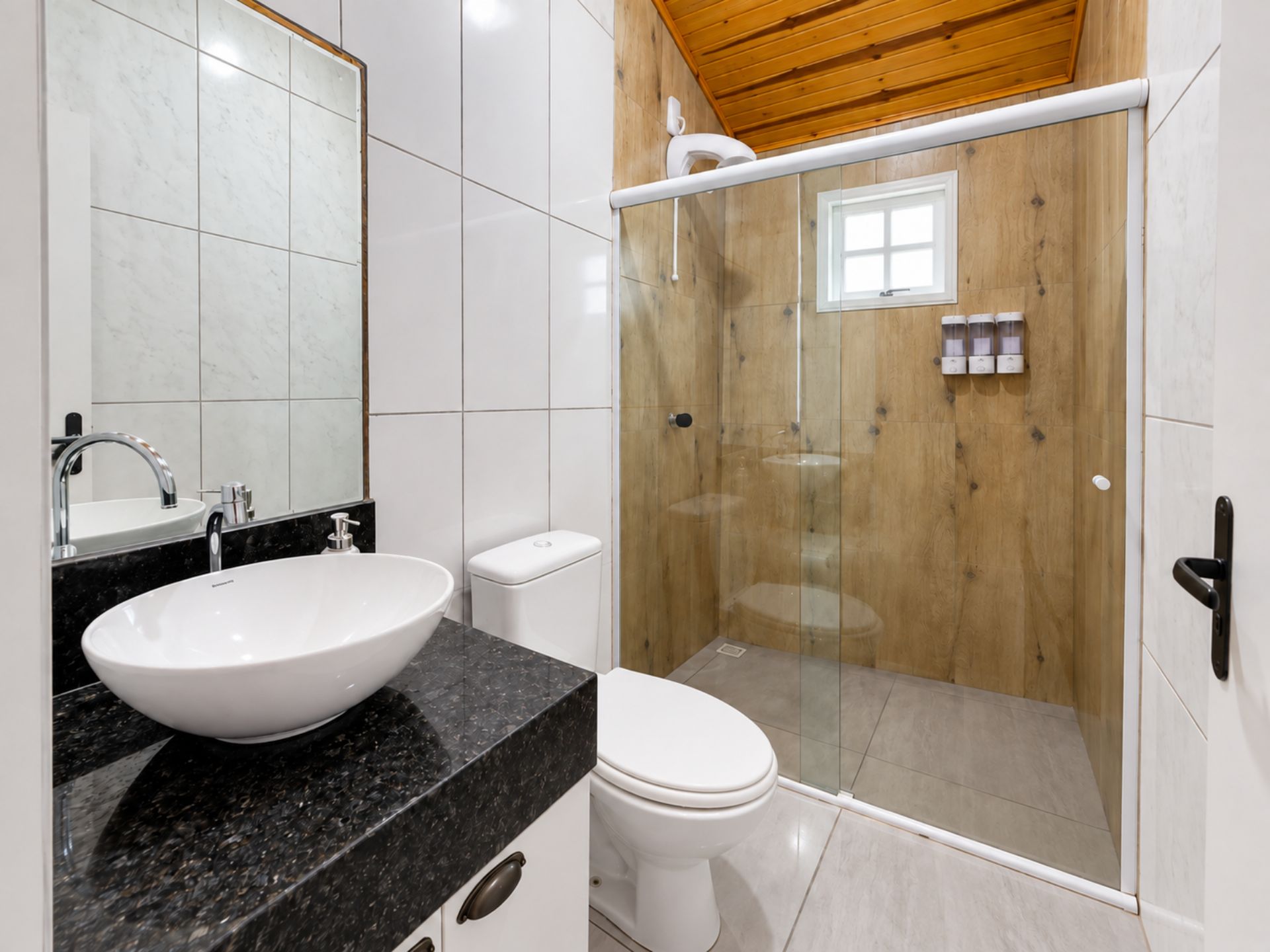 A modern bathroom with a large white sink, a toilet, and a glass-enclosed shower.