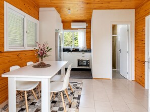 A compact kitchen with white cabinets, a dining table with chairs, and a view of the outdoors through the window.