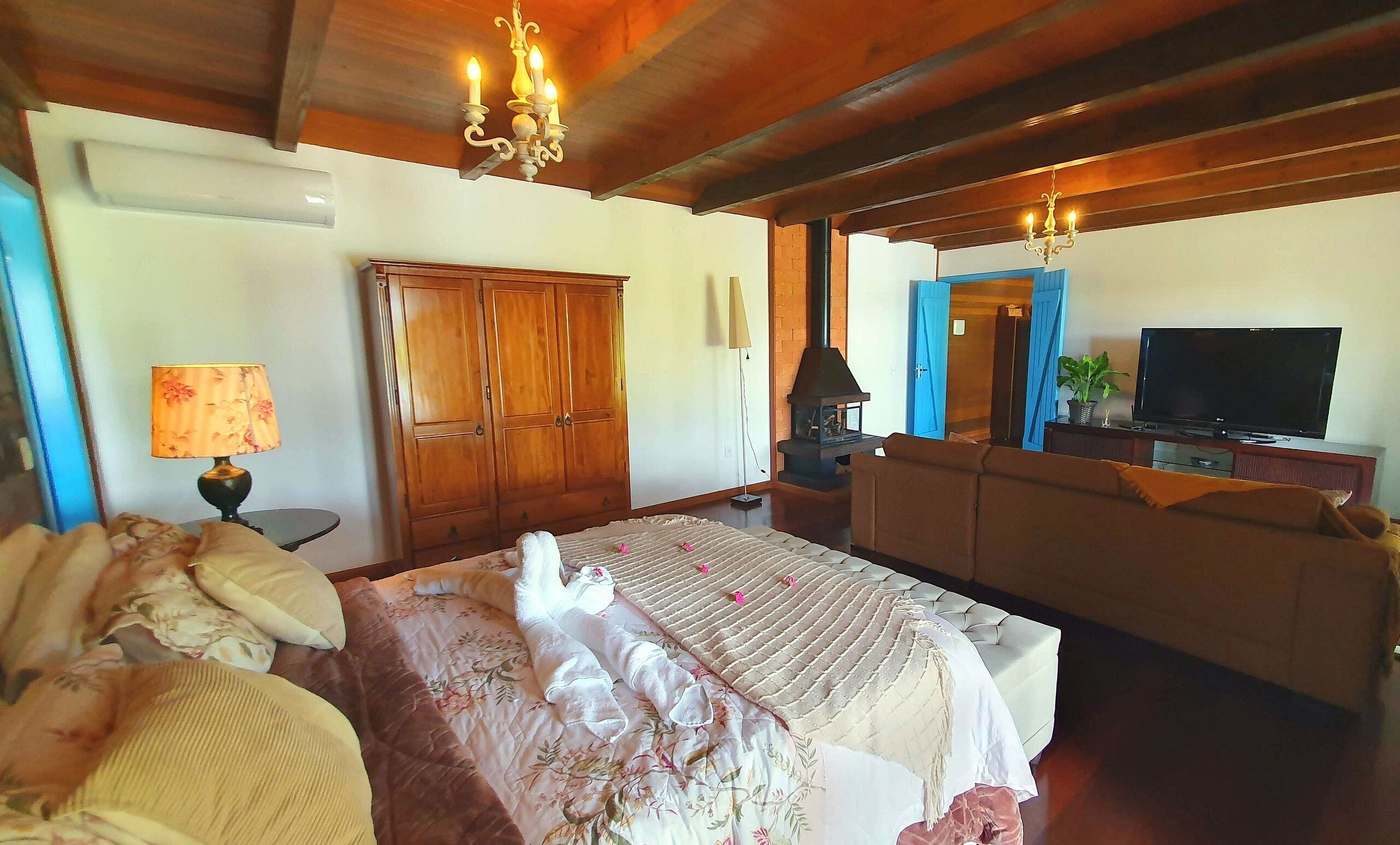 A bedroom with a bed, a wardrobe, a television, and a fireplace.