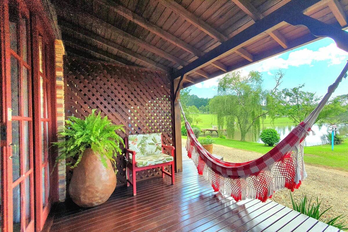 Une terrasse en bois avec un hamac, une plante en pot et une chaise.