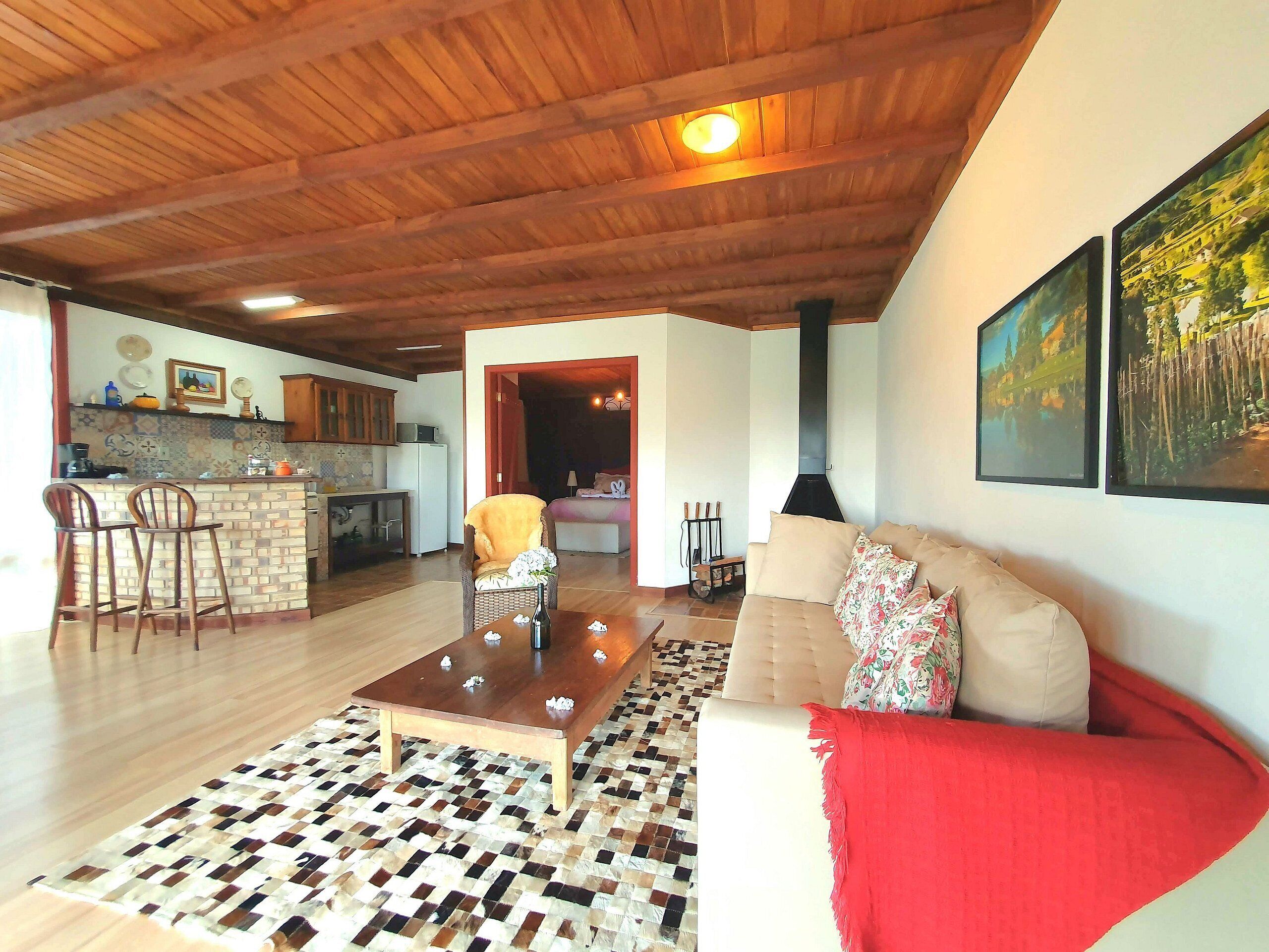 A spacious living area with a wooden ceiling, a sofa, a coffee table, and a patterned rug.