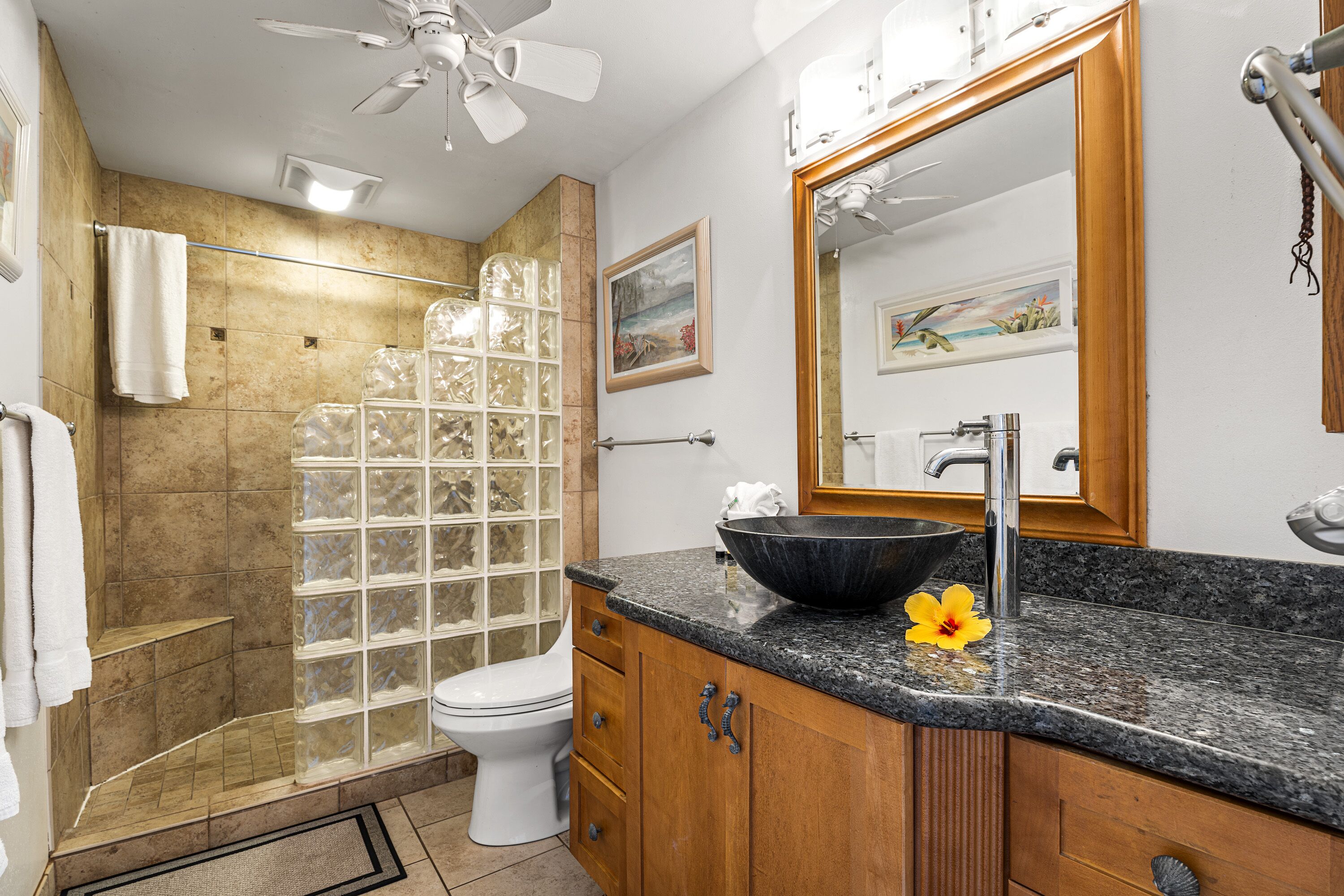 A bathroom with a shower, toilet, vanity, and a large mirror.
