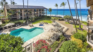 A hotel with a pool, lounge chairs, and a view of the ocean.